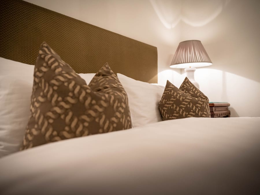 A neatly made bed with patterned pillows and a bedside lamp.
