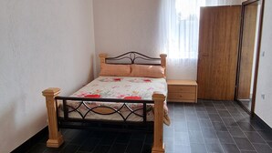 Une chambre à coucher avec un lit, un plafond en bois, une fenêtre avec des rideaux et une porte.