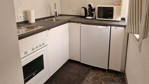 Une cuisine compacte équipée d’une cuisinière, d’un four à micro-ondes et d’un petit plan de travail.