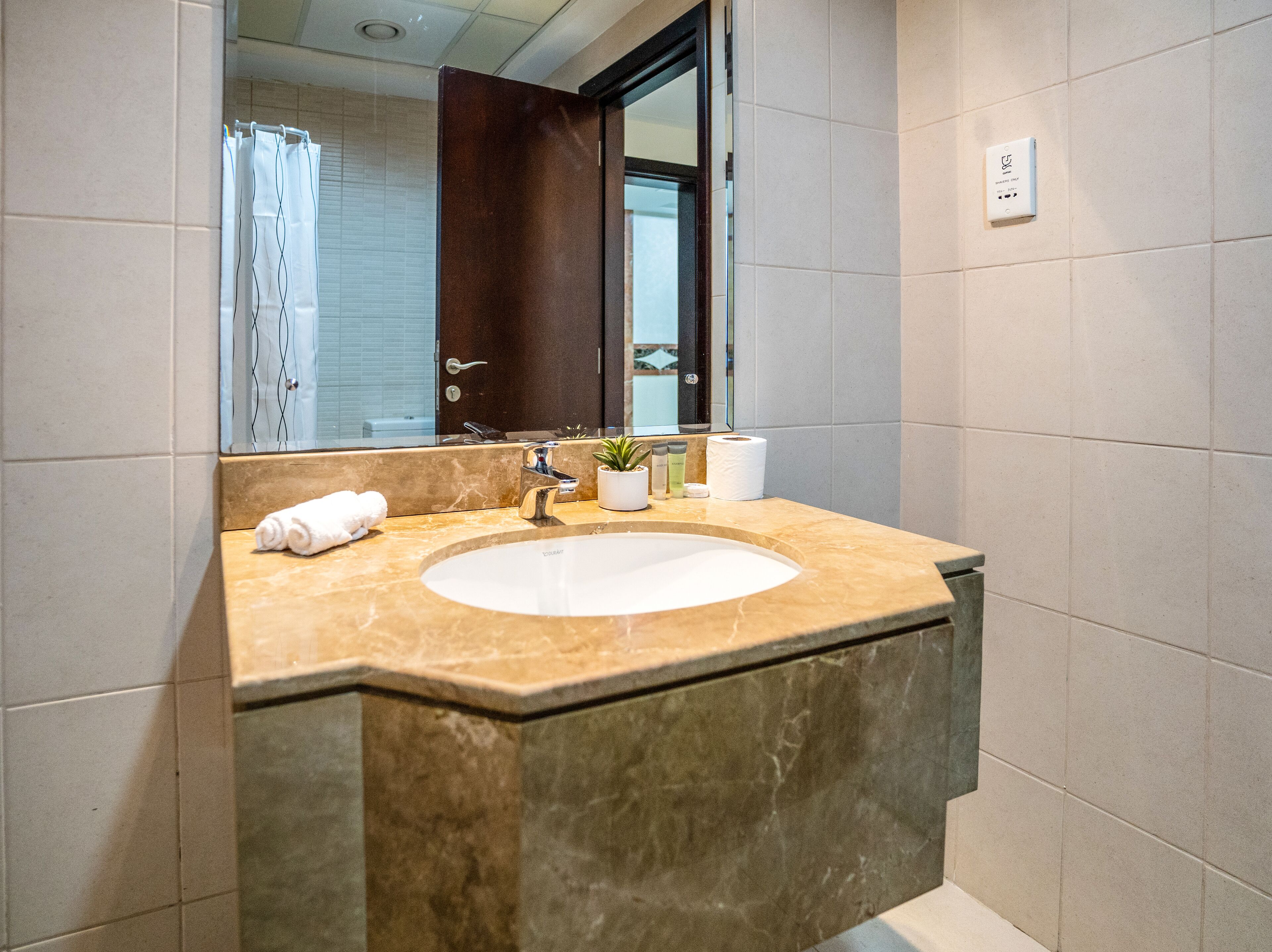 A bathroom with a marble sink, a mirror, a towel, and toiletries.