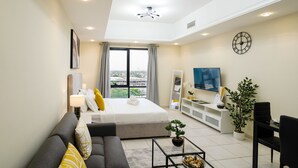 A modern hotel room with a large bed, a sofa, a TV, and a dining area. - Tanin - Luxurious and Contemporary Studio in JLT Cluster R (Dubai)