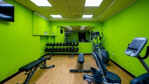 A gym with green walls, a bench, dumbbells, and cardio equipment. - Tanin - Luxurious and Contemporary Studio in JLT Cluster R (Dubai)