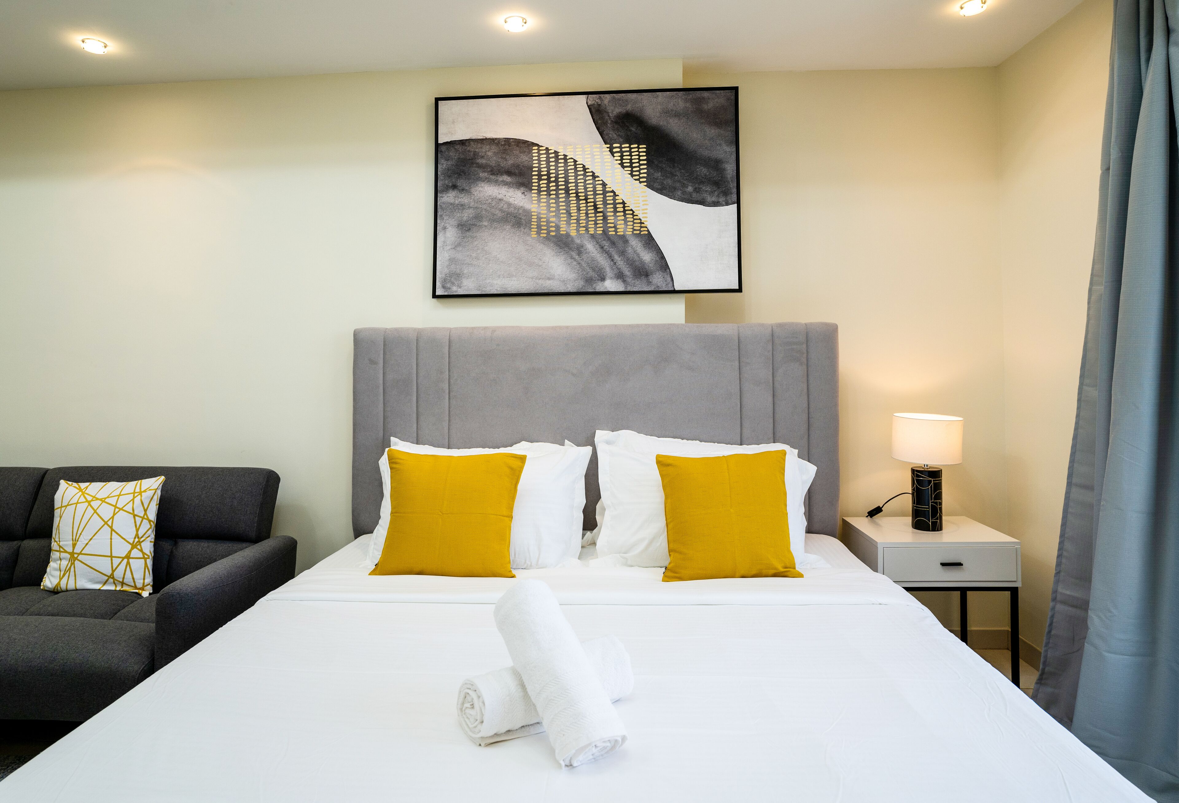 Una habitación de hotel con una cama, una mesita de noche, una lámpara y un cuadro en la pared.