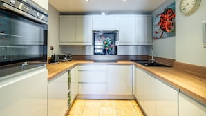 Eine moderne Küche mit Backofen, Kaffeemaschine und einem Kühlschrank mit farbenfroher Dekoration.