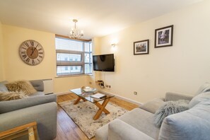 Relax in this stylish living room with a large wall clock, flat-screen TV, and plush sofas.