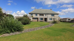A two-story house with a stone pathway leading to the front door, surrounded by well-maintained grass and shrubs. - sandwick bay guest house (Stornoway)