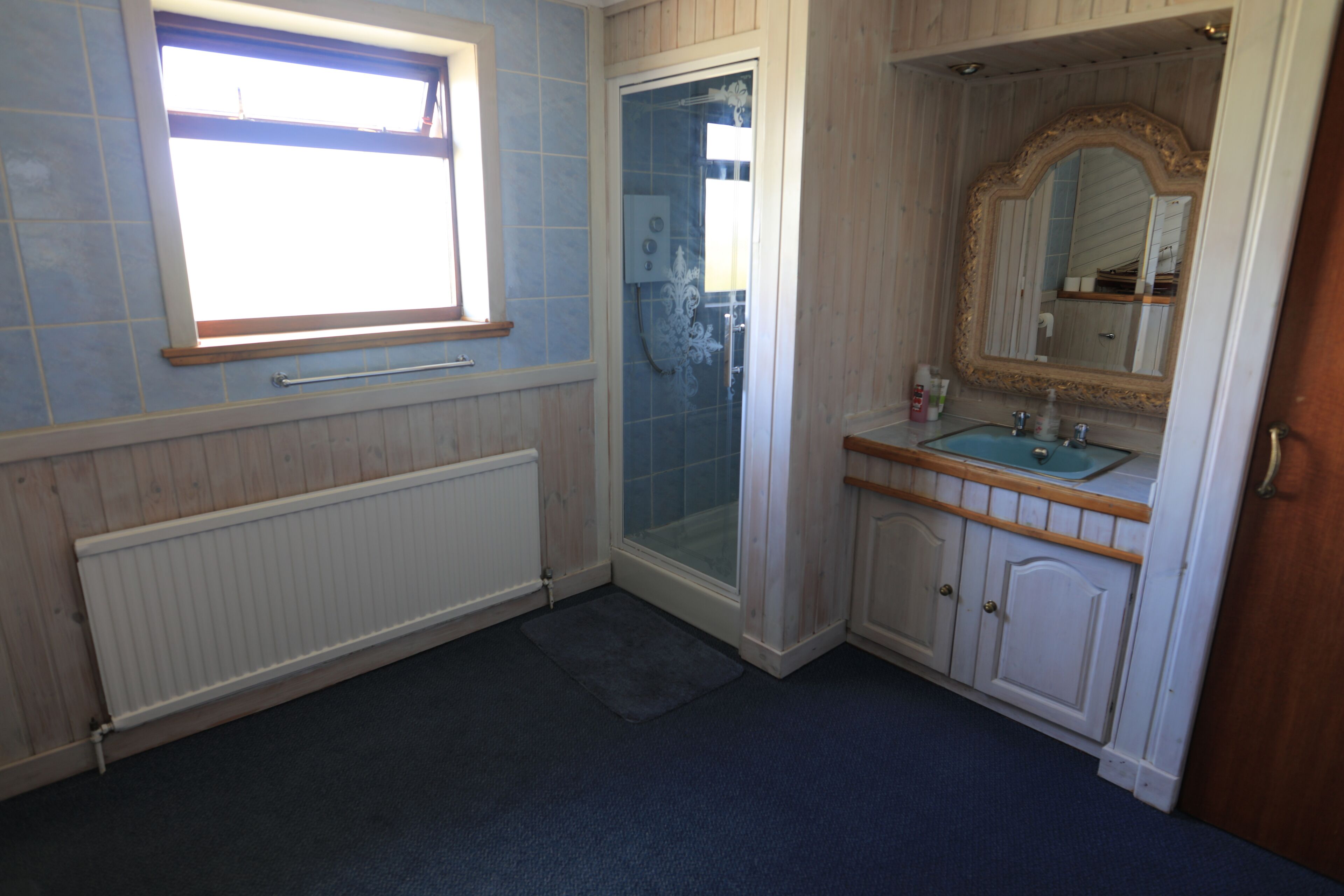 A bathroom with a shower, a sink, a mirror, and a window.
