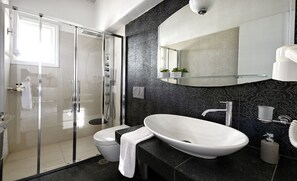 Un baño moderno con cabina de ducha de vidrio, un lavabo blanco y un espejo grande.
