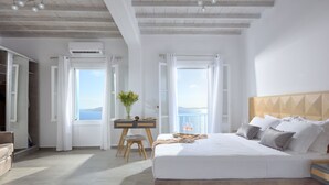 Un dormitori amb un llit gran, un escriptori amb una cadira i vista al mar.