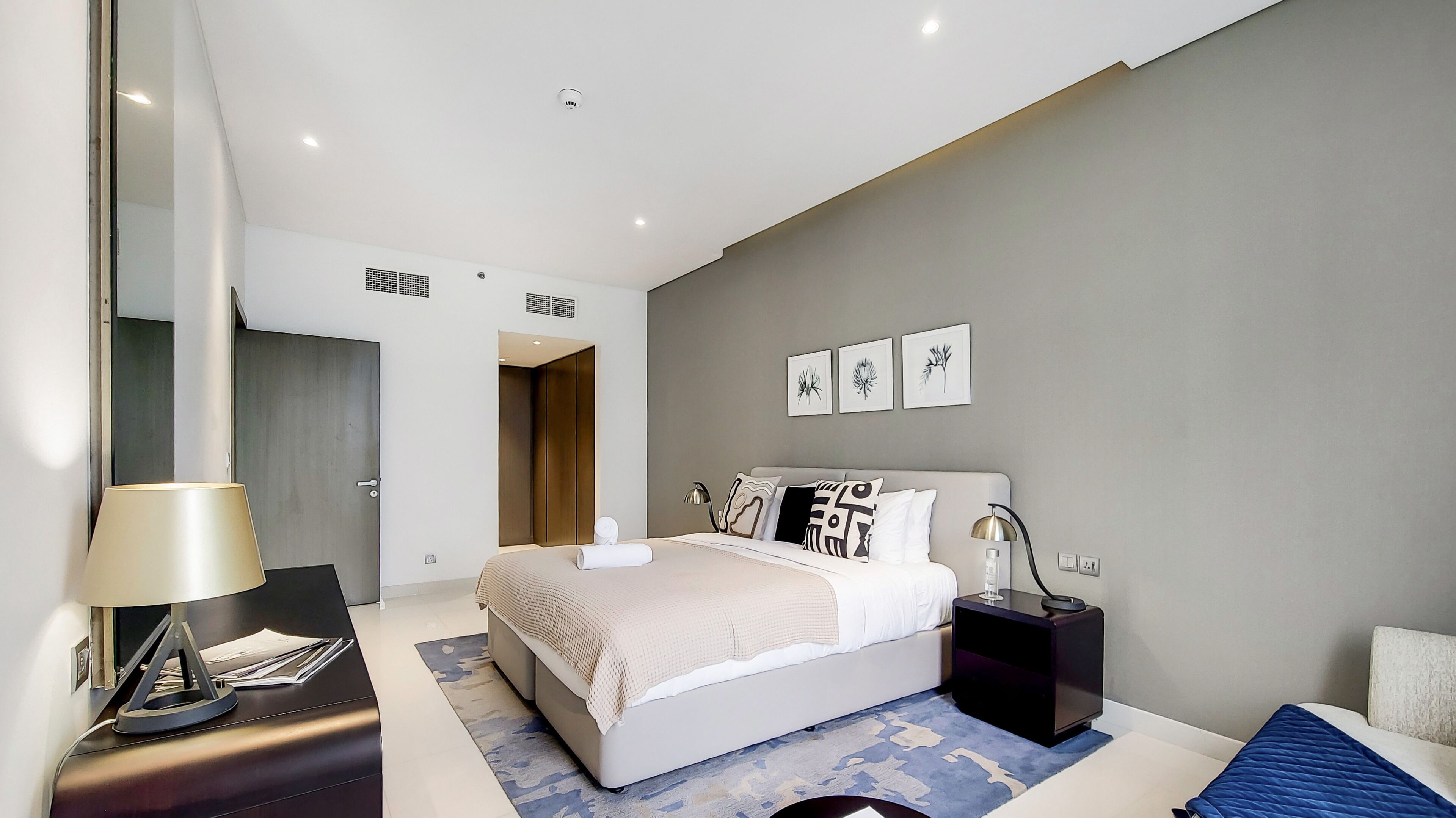 A modern bedroom with a bed, bedside tables, a desk, and a wardrobe.