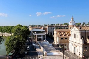 Une vue sur la ville, depuis les rives d’un fleuve, mettant en valeur son architecture historique, notamment un bâtiment remarquable doté d’un dôme et de colonnes.