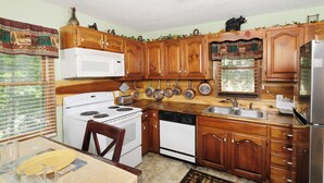 Une cuisine équipée de meubles en bois, d’une cuisinière, d’un four à micro-ondes, d’un lave-vaisselle et d’un réfrigérateur.