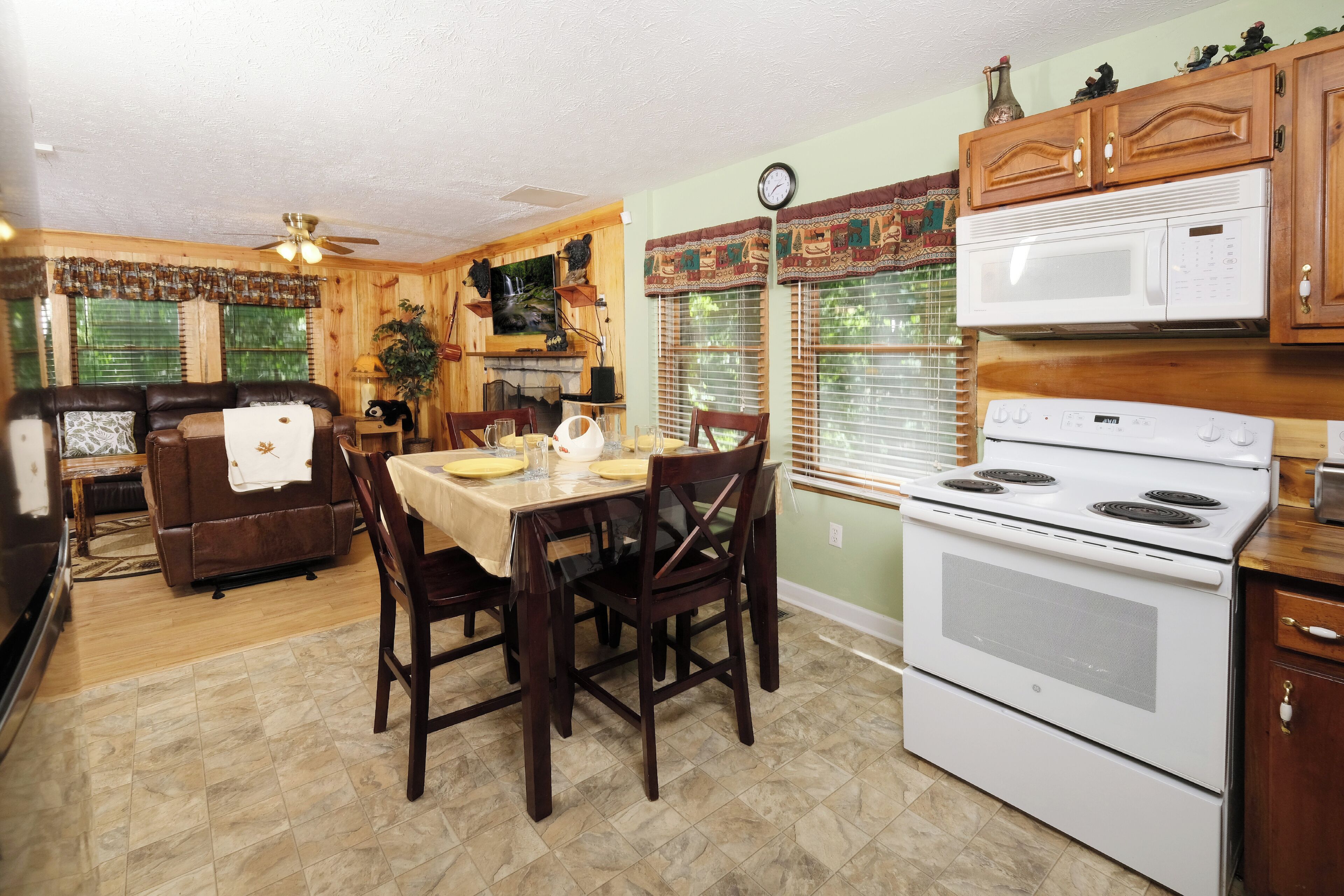 A kitchen with wooden cabinets, a microwave, stove, dining table with chairs, and a fireplace.
