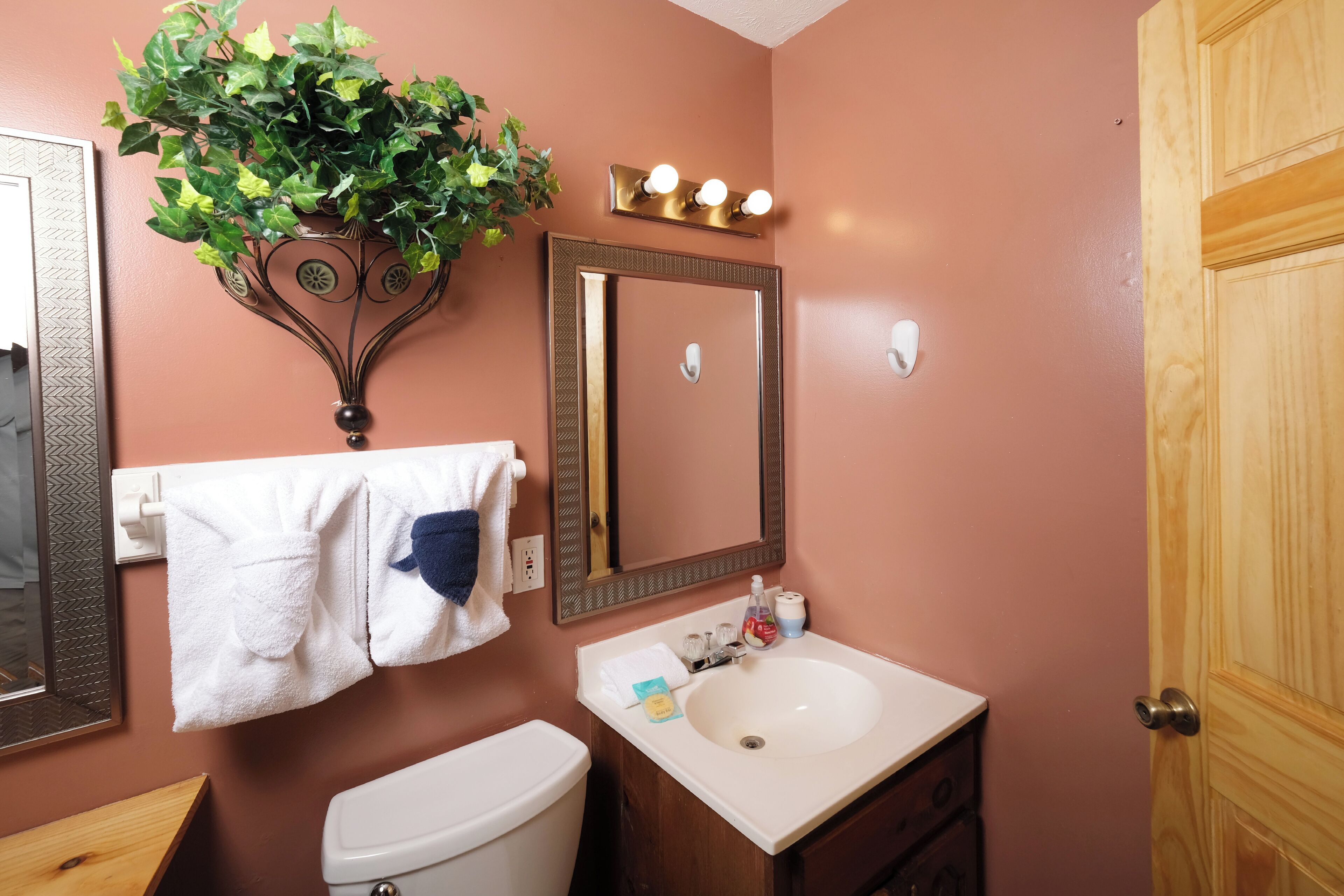 A bathroom with a toilet, sink, mirror, and towel rack.