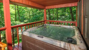 Un bain à remous sur une terrasse en bois, avec vue sur une forêt.