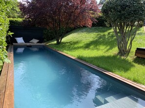 Relax by the serene pool surrounded by lush greenery and comfortable seating.