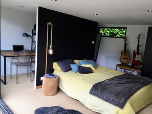 Relax in a serene space with a neatly made bed, desk, and comfortable seating.