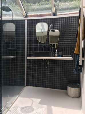 Features a sleek black tiled backsplash, large mirror, and minimalist sink area.