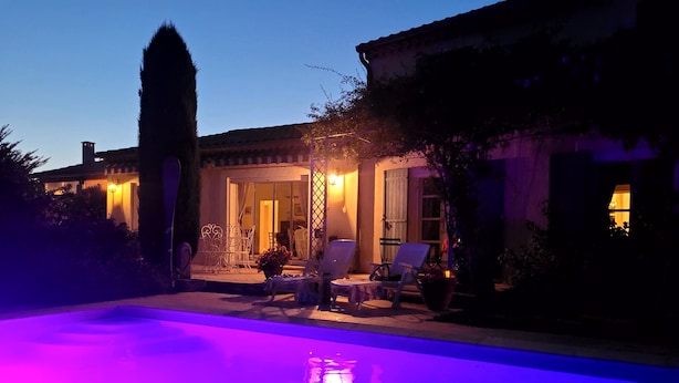 Un espace piscine avec des chaises longues et un patio couvert.