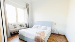 A bedroom with a bed, a bedside table, a lamp, and a window with curtains. - SUPERIOR APARTMENT (Roma)