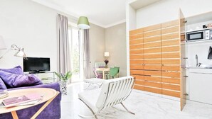 A modern living room with a purple sofa, a white coffee table, a TV, and a dining area with a white chair. - SUPERIOR APARTMENT (Roma)