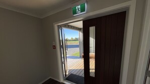 A hallway with a wooden floor leading to a door with a glass panel. - Lower Lodge (12 Bed) Pudding Hill (Methven)