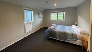 Una camera da letto con un letto, due finestre, un termosifone e un comodino.