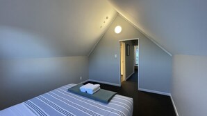 Une chambre à coucher avec un lit, une petite table et une porte donnant sur une autre pièce.