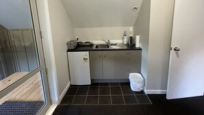 Une cuisine de taille réduite équipée d’un réfrigérateur, d’une cuisinière, d’un évier et d’une petite poubelle.