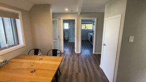 A spacious room with a wooden dining table, a kitchen area, and a bathroom visible through an open door. - Chalet 3 (5 Bed) Pudding Hill (Methven)