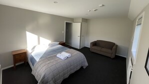 A bedroom with a bed, a nightstand, a chair, and a wardrobe. - Chalet 3 (5 Bed) Pudding Hill (Methven)