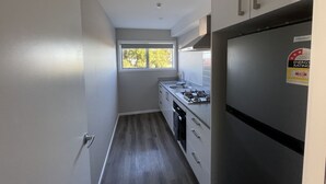 A narrow kitchen with a window, a stove, and a refrigerator. - Chalet 3 (5 Bed) Pudding Hill (Methven)