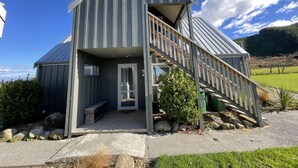 Ein modernes Gebäude mit Metallfassade, einer Holztreppe und einer kleinen Veranda.