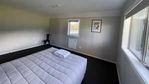 Ein Schlafzimmer mit einem großen Bett, einem Fenster, einem Heizkörper und einem gerahmten Bild an der Wand.