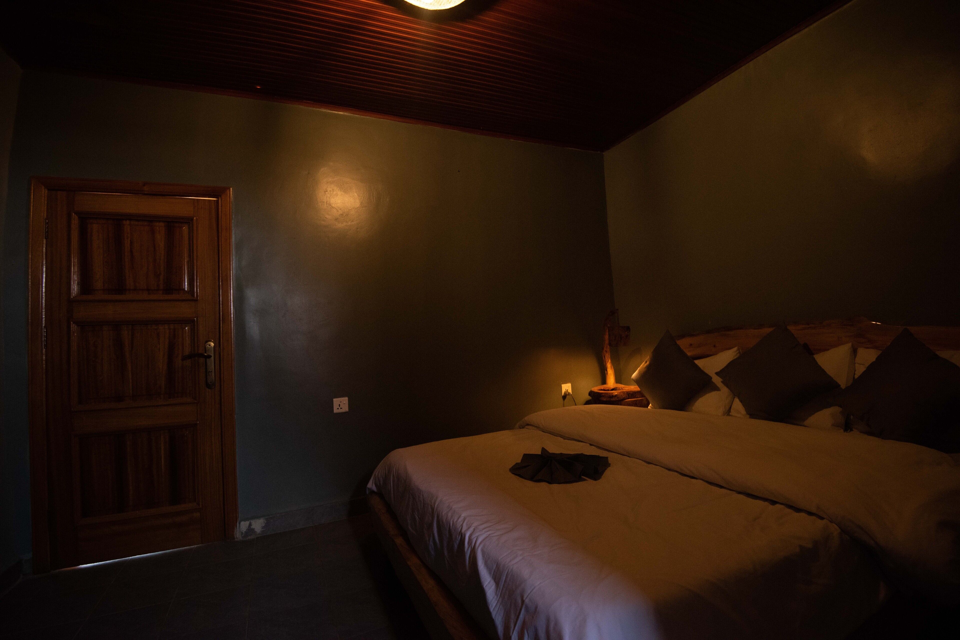 Une chambre avec une porte en bois, un lit avec des oreillers et une table de chevet avec une lampe.