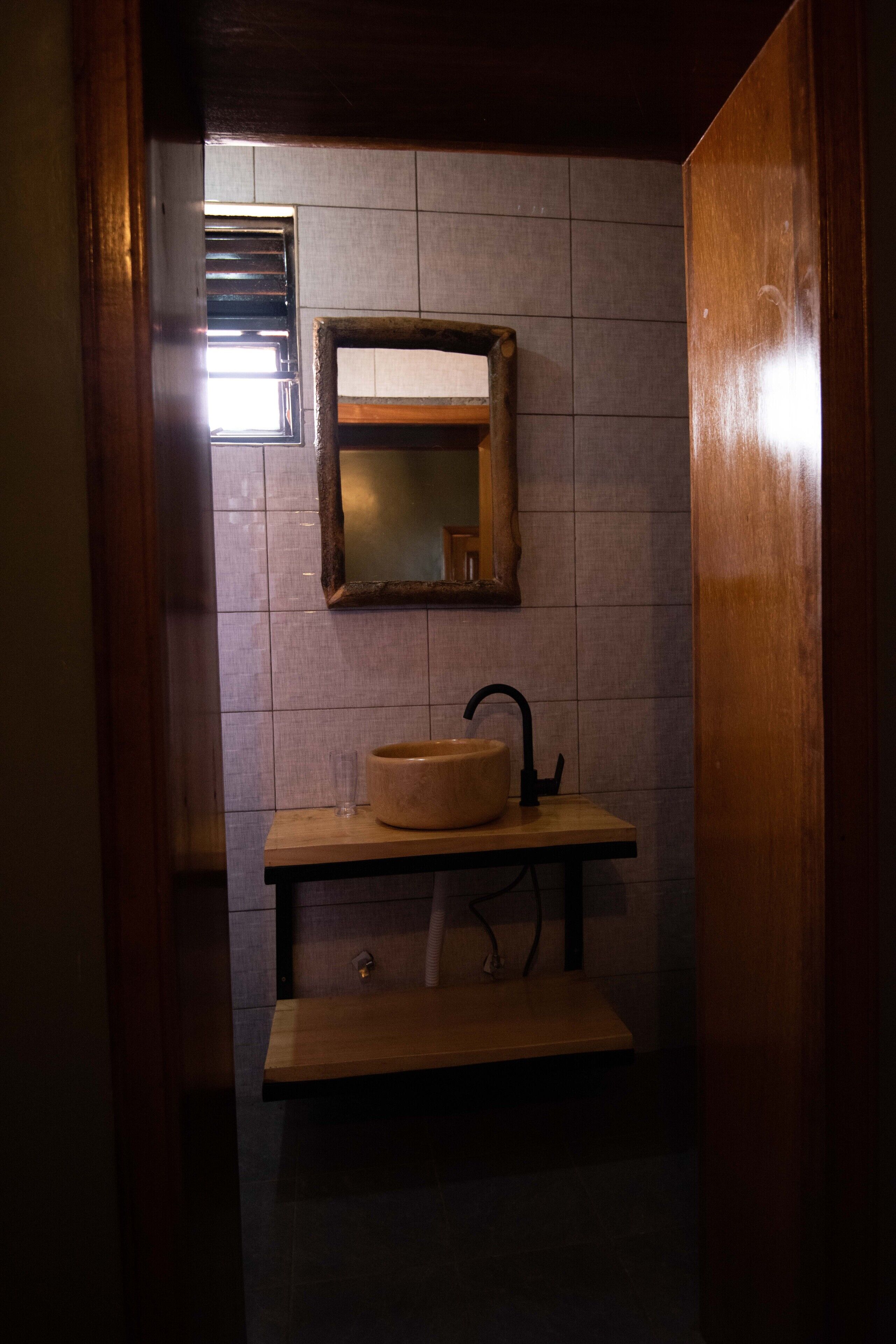 A small bathroom with a wooden vanity, a round sink, and a mirror.