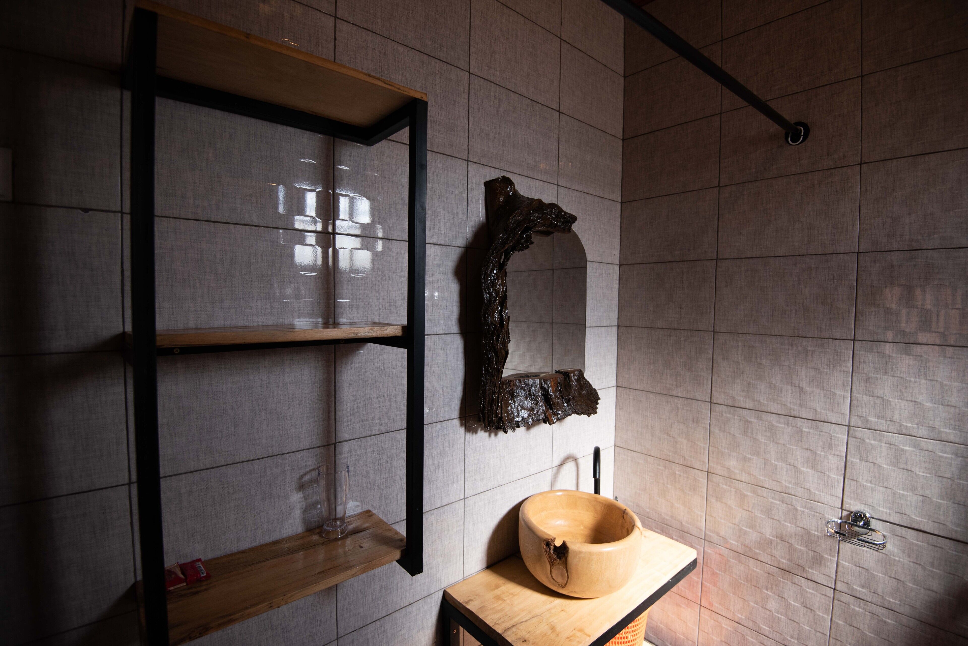 Un baño con estante de madera, un espejo grande y un lavabo de madera.