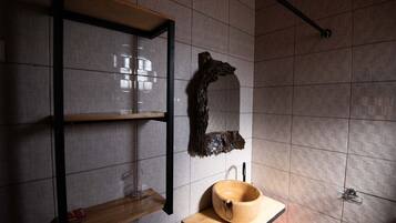 Un baño con estante de madera, un espejo grande y un lavabo de madera.