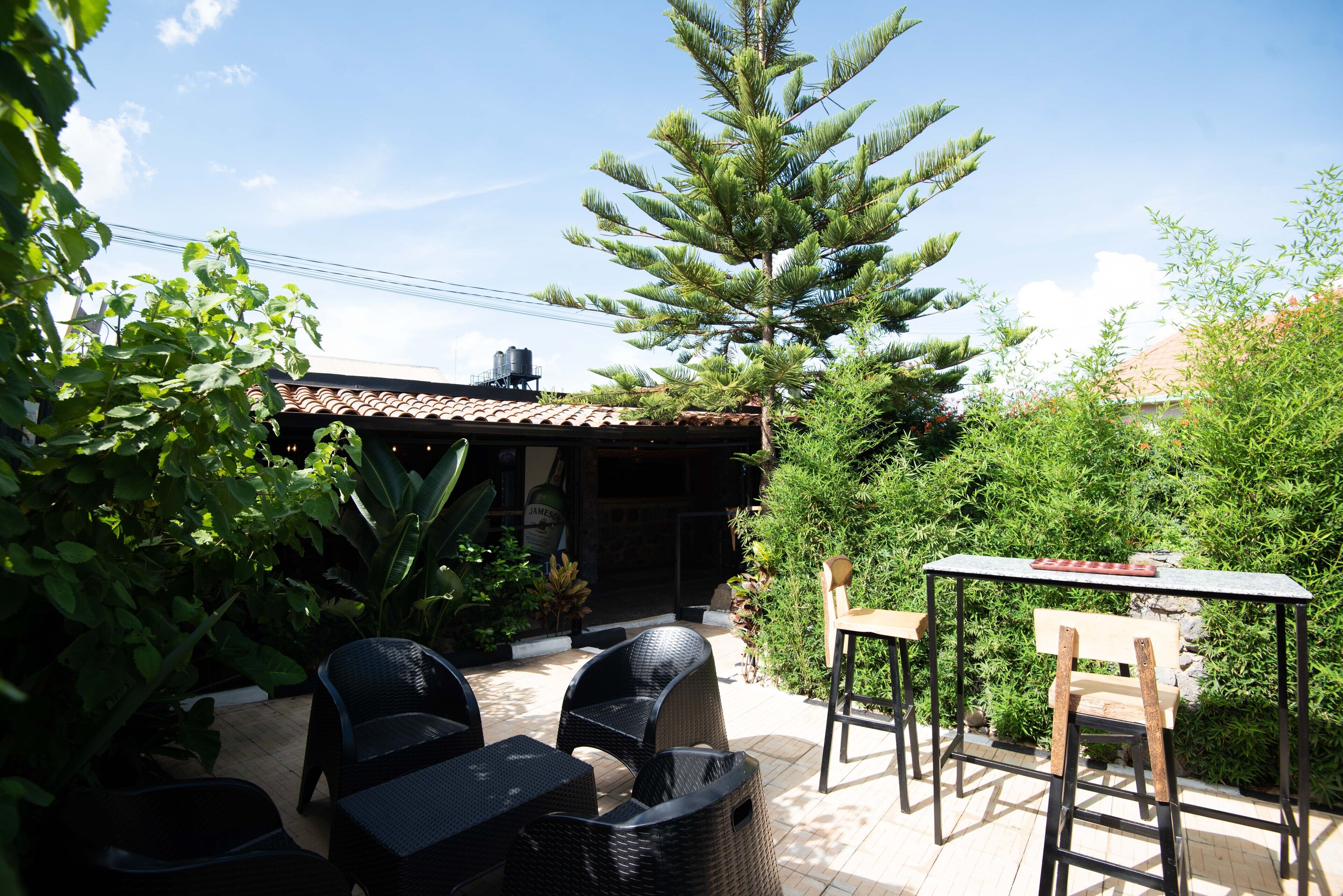 Eine Terrasse im Freien mit Korbmöbeln, einem Tisch und einer Bank.