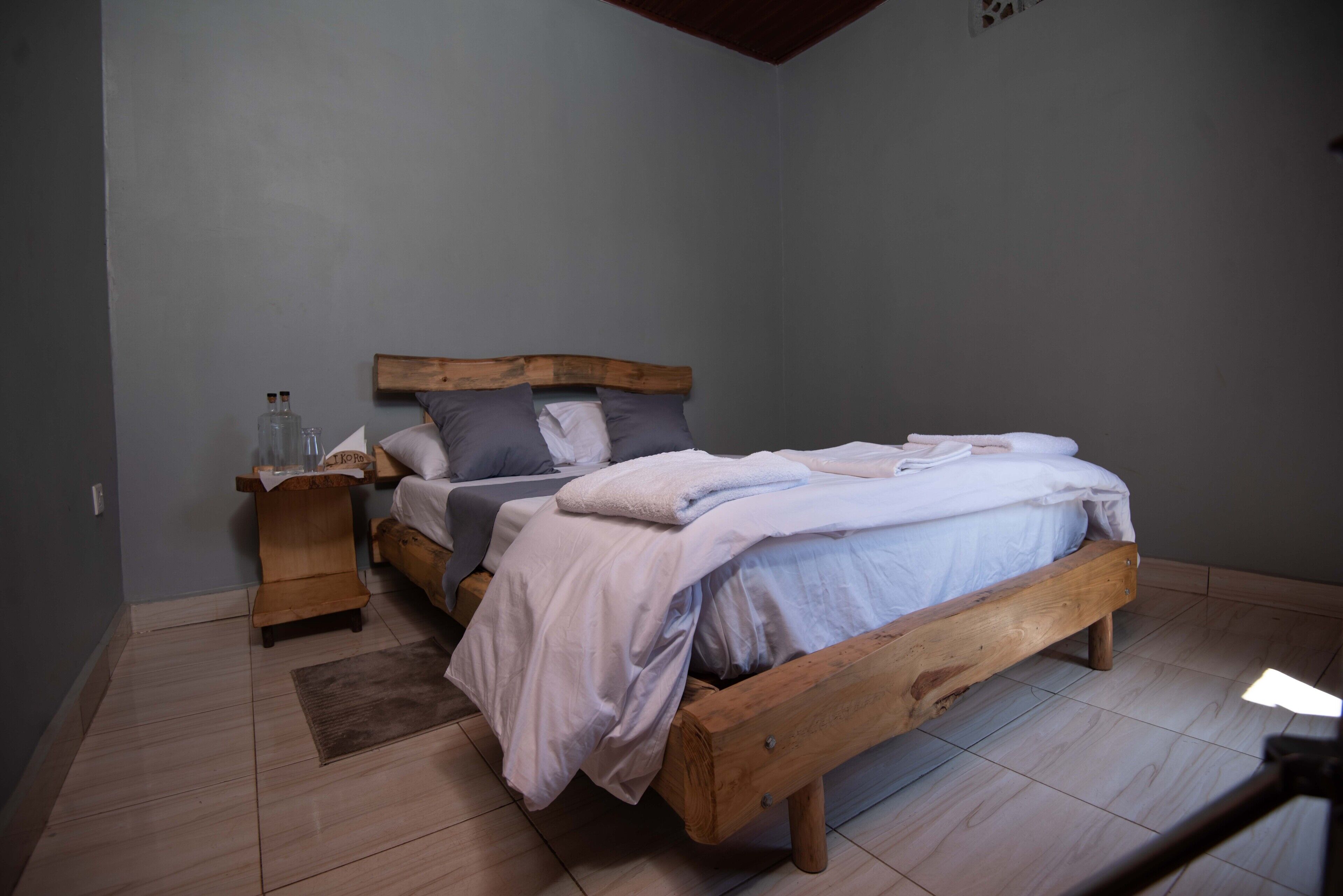 A bedroom with a wooden bed, a nightstand, and a bedside table with a lamp.