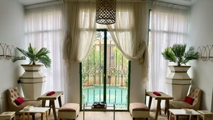 A room with a pool view, featuring two sofas, a small table, and a ladder leading to a balcony. - Sillage Palace Sky & Spa  (Marrakech)