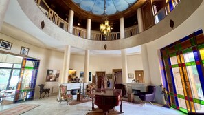 A grand hall with a high ceiling, a chandelier, a fireplace, and a large stained glass window. - Sillage Palace Sky & Spa  (Marrakech)