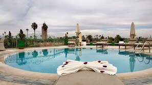A pool area with lounge chairs and umbrellas, a decorative pool edge, and a tower in the background. - Sillage Palace Sky & Spa  (Marrakech)