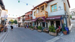 Una calle con cafés y tiendas, balcones de madera y mesas al aire libre.