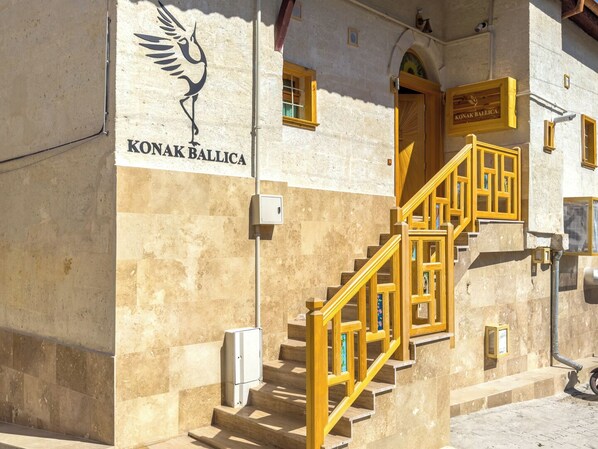 Un edificio con un letrero que dice "KONAK BALLICA" y una escalera con barandillas amarillas.