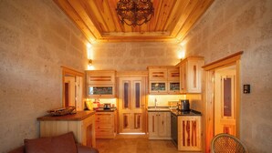 Una cocina acogedora con armarios de madera, una zona de comedor con una silla de mimbre y un sofá.