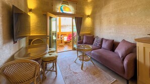 Una habitación acogedora con techo de madera, un sofá, un televisor, una mesa y una silla.
