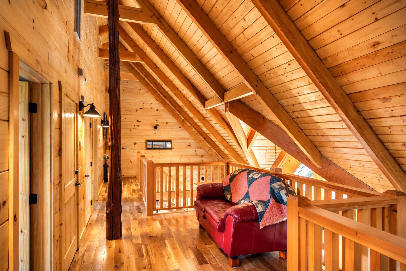 A wooden interior with a red leather sofa, wooden beams, and a staircase.