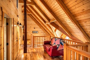 A wooden interior with a red leather sofa, wooden beams, and a staircase.