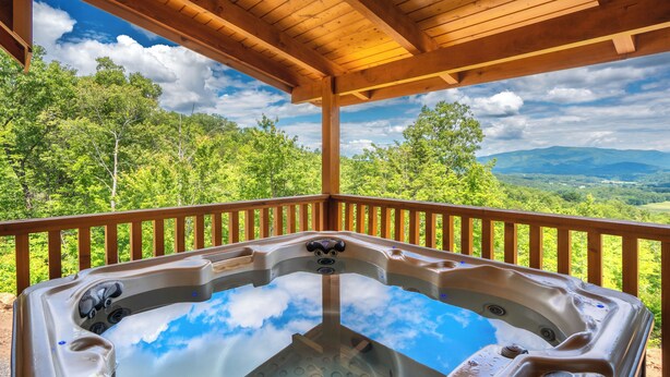Un jacuzzi bajo una pérgola de madera con una vista panorámica de las montañas.